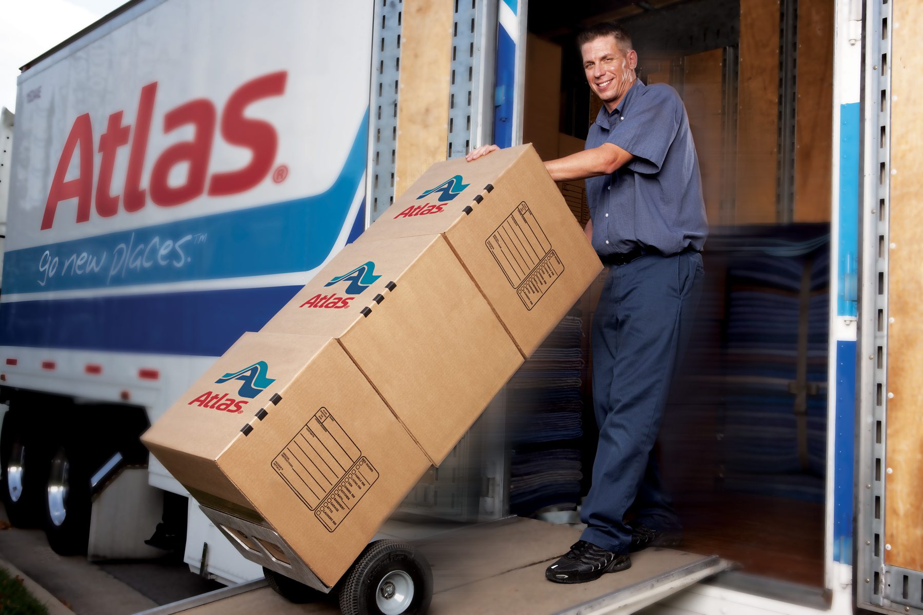 A person unloading cardboard boxes from an Atlas moving truck