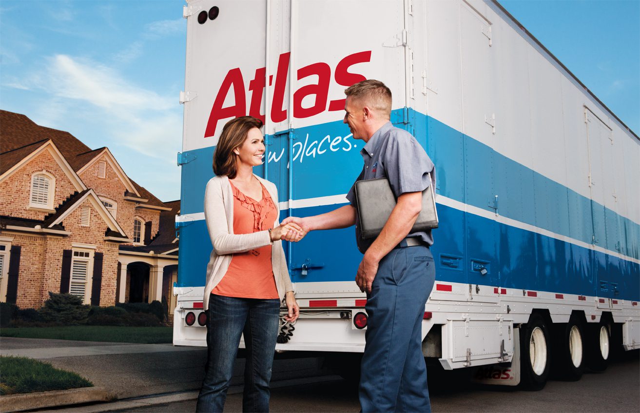 Two individuals shaking hands in front of an Atlas moving truck near a house